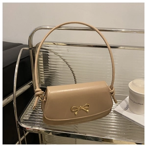 Detailed view of beige leather small square bag with elegant gold metal bow clasp