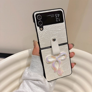 Detail of cream leather phone case for Samsung Z Flip with large pearl bow and hand strap