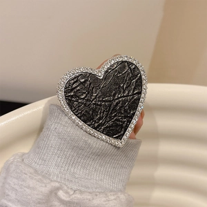 Detail of heart-shaped phone grip with black textured leather and sparkling rhinestones