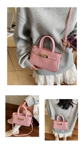 Detail view of pink crocodile embossed handbag with golden turn-lock and adjustable strap