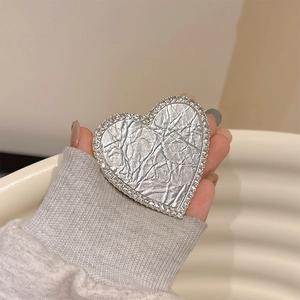 Sparkling silver textured heart phone grip stand with rhinestone borders held by a hand