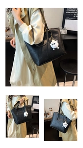 Close-up of black leather tote with floral embossing and white plush monster pendant
