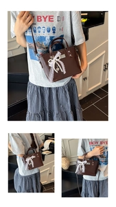 Detail of dark brown leather bucket bag with lace bow, pearls, and heart charm
