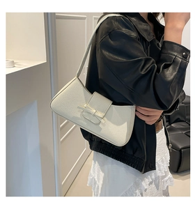 Bolso de hombro blanco con lazo y textura granulada llevado por una modelo