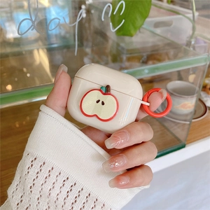 Detail of cream AirPods case with apple illustration and red clip held in hand