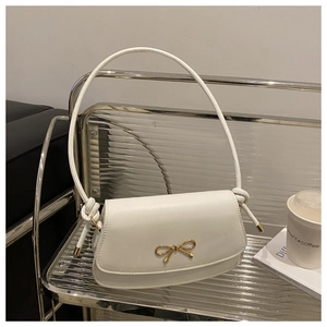 Detail of white matte leather bag featuring a gold bow clasp and elegant knotted strap