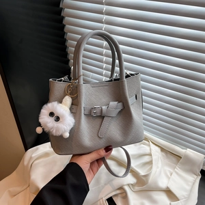 Grey woven bucket bag with metal buckle and plush monster charm for women in 2025 style