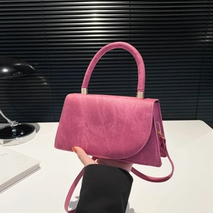 Minimalist rose pink crossbody bag with matte texture and cylinder handle on desk