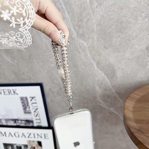Detail of luxury rhinestone phone lanyard with pearl charm held against lace sleeve