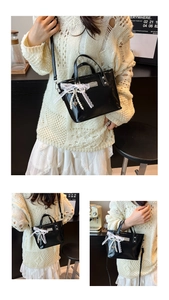 Detail of black bucket bag with white lace bow, pearl charm and heart pendant accents