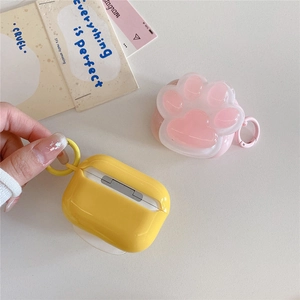 Close-up of pink cat paw and yellow AirPods silicone cases with portable keychains