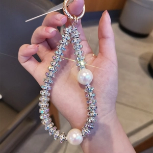 Detail view of pearl and rhinestone phone strap featuring a gold metal ring clasp
