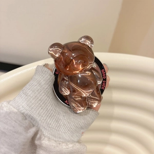 Macro shot of amber resin bear phone grip with Good Luck text on cream wave background