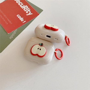Macro shot of cream silicone AirPods case featuring 3D red apple design and metal ring