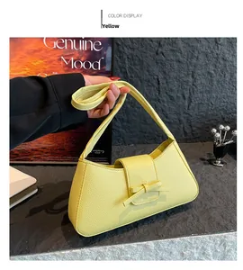 Detail view of bright yellow faux leather handbag with litchi texture and bow accent
