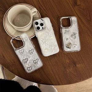 Custodie iPhone perlate con motivi a cuore e orsetto e glitter su un tavolo di legno