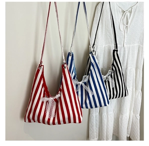Detail von gestreiften Canvas-Tote-Bags mit feinen Spitzenschleifen in verschiedenen Farben
