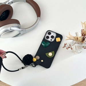 Black iPhone case with 3D heart shapes, plush ball charm and hand strap on modern desktop