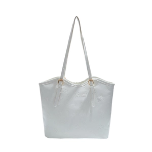White faux leather tote bag with embossed butterfly floral patterns and gold buckles