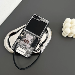Detail of tweed Samsung Z Flip6 case with plush bear charm and black leather lanyard