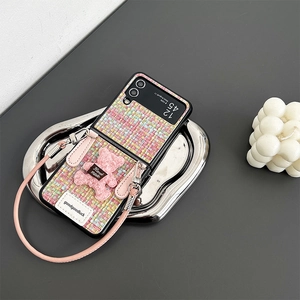 Detail of pink tweed folding phone case with plush bear charm and leather hand strap