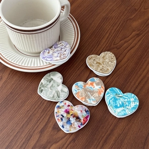 Set of 6 heart-shaped cell phone socket grips with diverse marbled textures on a wooden table