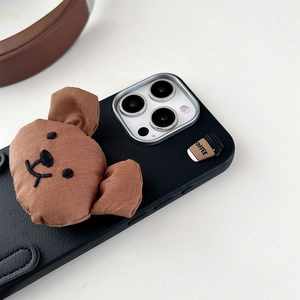 Close-up of cute brown plush bear and coffee cup charm on leather iPhone case