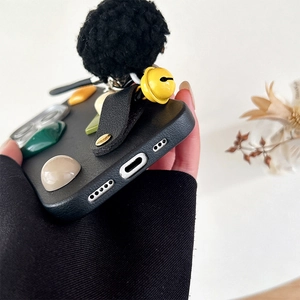 Close-up of black leather texture phone case with plush ball and precise bottom cutouts