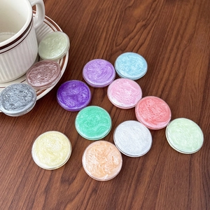 Mix of colorful round glitter sealing wax beads on a textured wooden desk surface