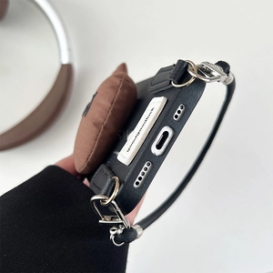 Detail of iPhone case with brown plush bear, black leather strap and luck label