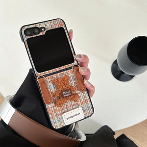 Detail of tweed folding phone case with plush bear ornament and leather handle decoration