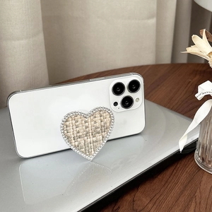 Détail du support de téléphone en forme de cœur avec tissu tissé beige et strass