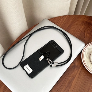Detail of leather phone case with flower ring buckle and long crossbody strap on a laptop