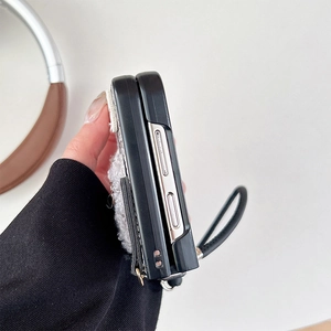 Close-up of folding phone case with black leather strap and white plush bear detail