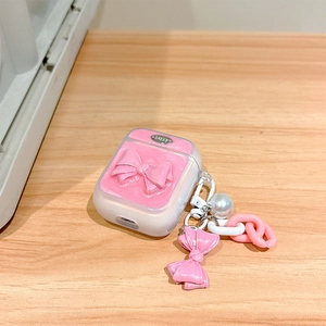 Macro detail of pink glitter AirPods case featuring a Happy metal tag and pearl chain