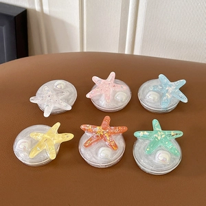 Detail of colorful glitter starfish phone stands with white pearls on a leather surface