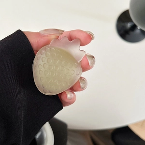 Detail of strawberry shaped phone grip with matte translucent texture in hand
