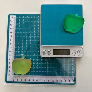 Macro shot of green frosted apple phone grip on scale weighing 33 grams