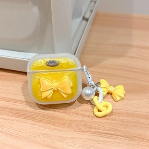 Detail of yellow glitter AirPods case with 3D bow, pearl strap, and Happy metal tag