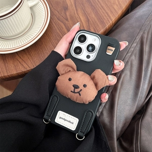 Detail of iPhone case with leather texture, plush bear charm, and metal lanyard hooks