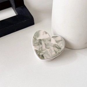 Macro shot of heart-shaped phone grip featuring green and white marble texture resin