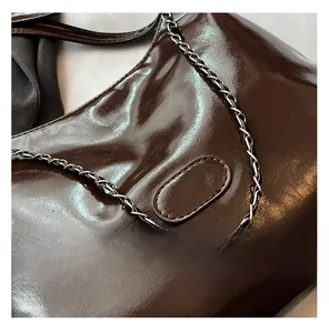 Detail of dark brown glossy hobo bag with classic leather and metal chain shoulder strap