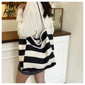 Detail view of large striped canvas tote bag with wide shoulder strap on a model
