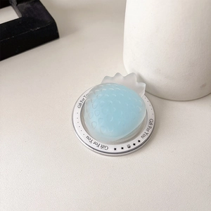 Detailed top view of a light blue strawberry phone grip on a white textured desk