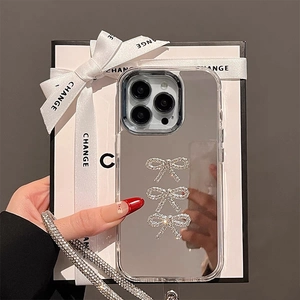 Detail of mirror iPhone case featuring sparkling rhinestone bows and a luxury wrist strap