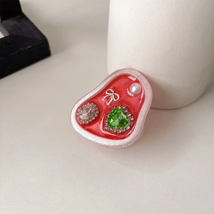 Detailed view of red heart phone grip with rhinestones, bow, and pearl embellishments