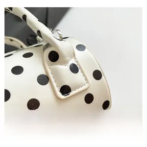 Dettaglio del motivo a pois e trama in pelle premium su questa borsa baguette alla moda