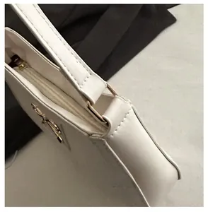 Detailed view of luxury white leather shoulder bag with golden hardware and metal logo