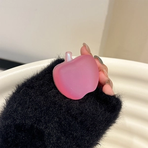 Detail of a pink matte apple-shaped hair clip held by hand against a soft background