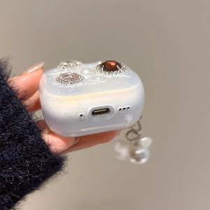 Detailed view of white pearl earbuds case with red rubies, pink crystals and side pendant